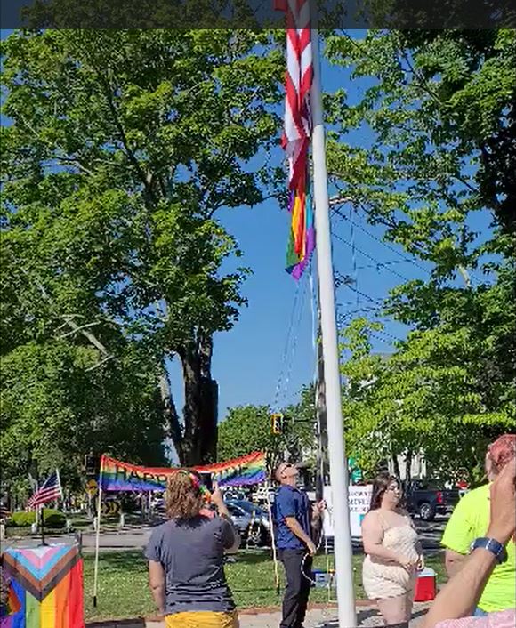 Facilities Director Chris Hartman raises the American and LGBTQ+ flags