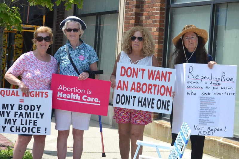 People at Reproductive Justice rally hold signs saying, “Equal rights equals my body, my family, my life, my choice!,", "Abortion is Health Care,” “Don’t want an abortion don’t have one,” “Repealing rights means a death sentence for poor women.”