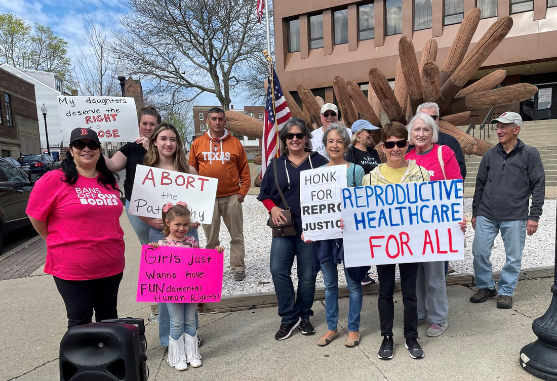 Reproductive Justice Rally attendees hold signs saying, 